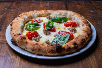 Pizza napoletana con pomodori, salsiccia, mozzarella e basilico 