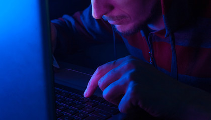 hacker typing on a keyboard in the dark background, stealing information from laptop