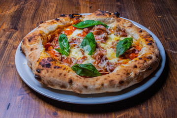 Pizza napoletana con pomodori, mozzarella, basilico e pancetta