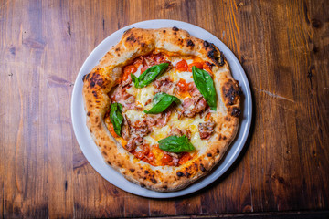 Pizza napoletana con pomodori, mozzarella, basilico e pancetta
