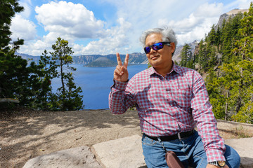 A retired Asian man happy and enjoy a holiday trip to celebrate the United States Independence Day at Crater Lake, Oregon National Park.