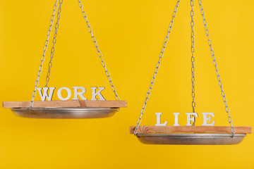 Work vs life. Balance concept. Scales on yellow background, close up