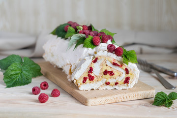 Meringue roll cake with cream and fresh raspberries. Roulade, summer dessert. Selective focus, horizontal orientation.