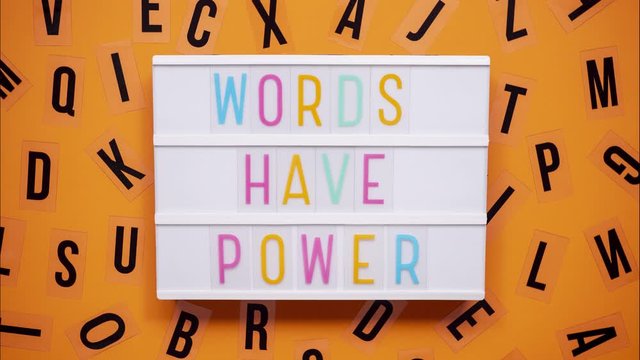 WORDS HAVE POWER sign on a letter board with letters being animated around. Orange background.