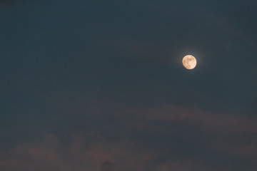 Moon in the sky during the evening besides clouds