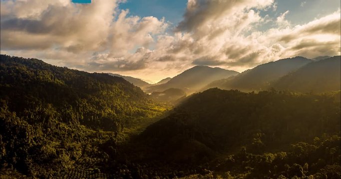 Aerial drone hyperlapse timelapse of beautiful tropical valley between mountains. The first rays of the rising sun break through the clouds and clouds. The last rays of the sunset hit the tree crowns.