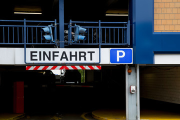Entrance of a car parking garage with signal lights and the sign "Einfahrt"