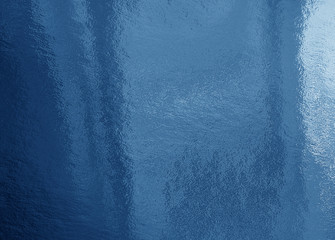 Blue foil background with highlights and uneven texture