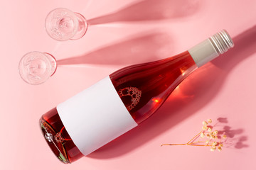 Bottle of rose wine and glass with long shadows.