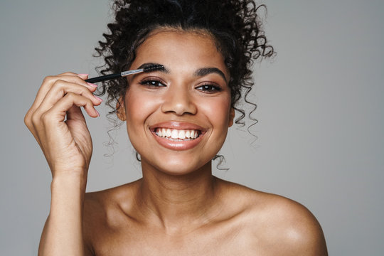 Image of african american woman using eyebrows brush and smiling