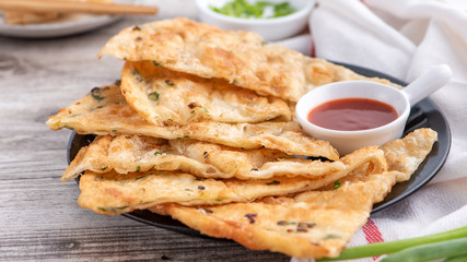 Taiwanese food - delicious flaky scallion pie pancakes on bright wooden table background, traditional snack in Taiwan, close up.