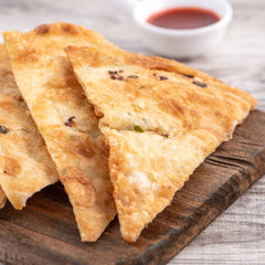 Taiwanese food - delicious flaky scallion pie pancakes on bright wooden table background, traditional snack in Taiwan, close up.
