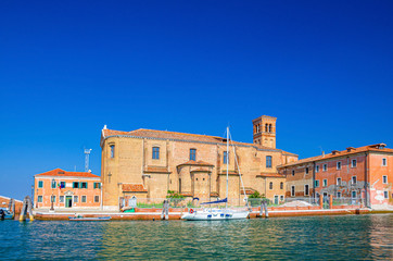 Fototapeta na wymiar Saint Domenico catholic church Chiesa di San Domenico and white yacht near island in lagoon, Chioggia town historical centre, blue sky background in summer day, Veneto Region, Northern Italy