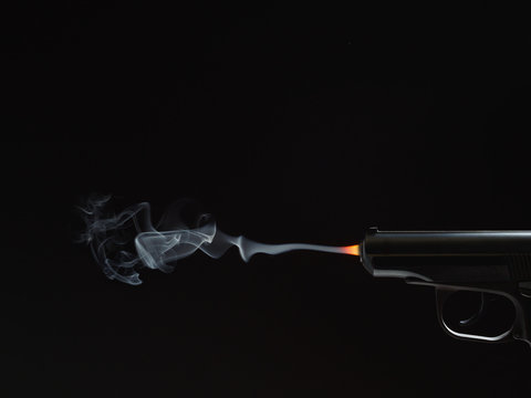 black silhouette of a gun with fire and smoke