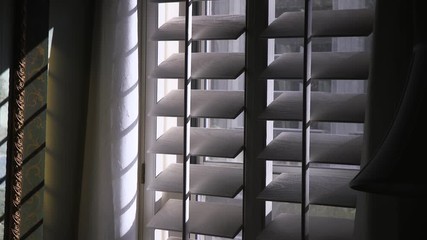 Light filters through white wooden shutters casting interesting shadows. - Powered by Adobe