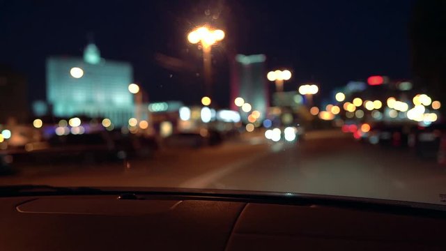 night city view from windshield of automobile, blurred lights at darkness