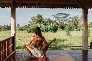 Young woman practicing yoga duringyoga retreat in Asia, Bali. Sit in lotus pose, Meditation,...
