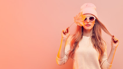 Fashionable hipster woman in Trendy autumn fall outfit, stylish hair, makeup. Blonde model in jumper, fashion jeans having fun smiling. Beautiful girl in autumnal beanie hat with maple leaf