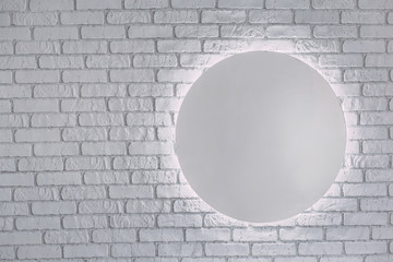 round mirror without reflection hanging on white gray brick wall