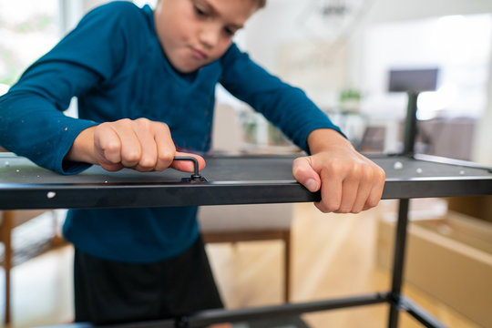 Close up view of a boy using allen wrench to assemble furniture