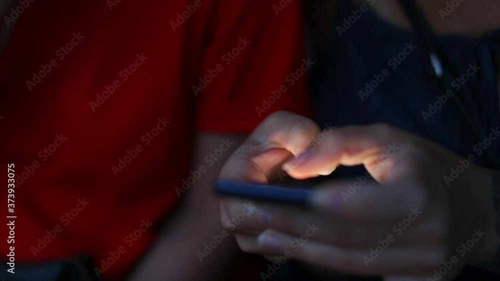 Poster close-up of the phone in the hands of a woman in the dark. using the internet in a smartphone for co
