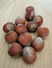 A handful of whole hazelnuts lie on a wooden table.