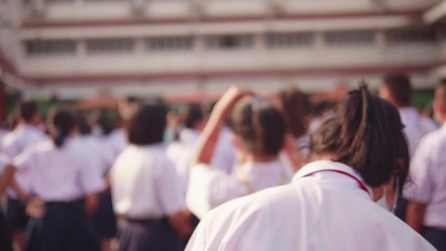 The strong sunlight in the morning while the Asian high school students in white uniform wearing the masks stand in line during the Coronavirus 2019 (Covid-19) epidemic.