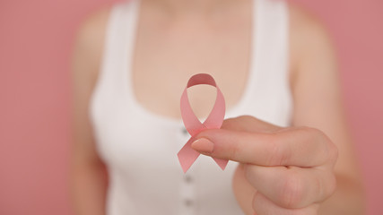 Pnk october, brest cancer awareness ribbon in the hand of a young unrecognzable woman. High quality...