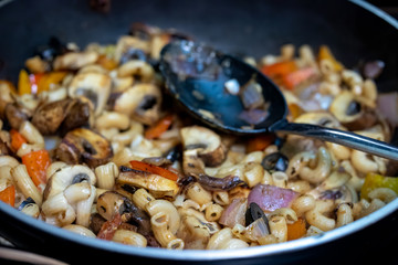 Pasta dinner with mushrooms, olives, onions in a pan with spoon