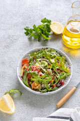 Fresh salad mixed with arugula, tomatoes, cucumbers and grated cheese  on concrete background top view. Healthy food.