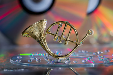 French horn on a multicolor background. Musical instrument with water drops on the background of the CD disk. Copy of the space.