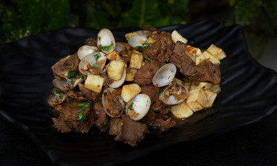 porc tenderloin and clams  carne de porco á alentejana  on a black plate