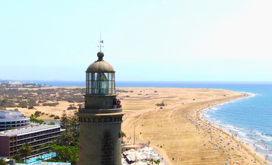 Faro majestuoso junto a paradisíaca playa de arena rubia y mar azul