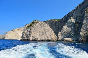 Gray rocks on the blue waters of the Mediterranean Sea in Greece. Motorboat traces on the water