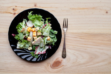 Caesar salad on black plate and rustic wooden table