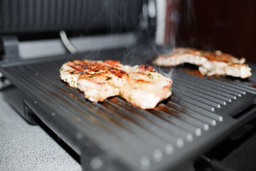 Marinated steak is grilled. Cooking process. Fried meat on a homemade electric grill