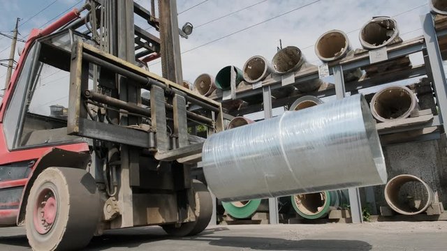 Forklift driver loads Rolls of steel sheet. Industrial warehouse with rolls of steel sheet