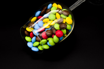 Chalice filled with colored chocolates on a black background