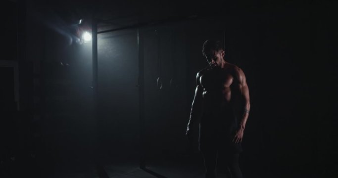 In the dark cross fitness class bodybuilding man with the sweating body in front of the camera