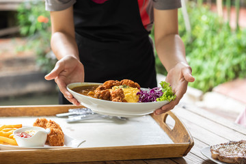 female waitress hold special dish curry rice topped wih fried chicken and scrambled eggs