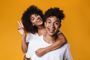 Image of couple gesturing peace sign while piggyback riding