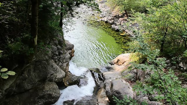Close up Rindbach waterfall from wooden bridge with forest and small lake. Austria alps mountain