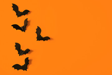 Fototapeta premium Cartoon halloween background black bats on orange backdrop. Bright holiday backdrop for your design. Dark and moody background. Place for text.