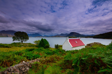 A single red roofed croft on the shores of Loch Shieldaig on the Applecross Peninsula in the Highlands of Scotland © cliff