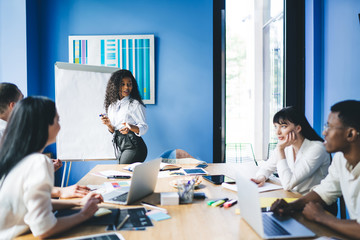 Confident ethnic businesswoman doing presentation for coworkers at office