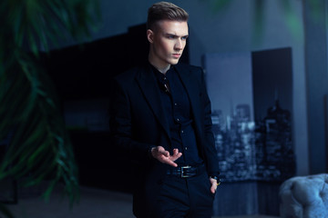 a man stands in an apartment in an expensive handsome suit