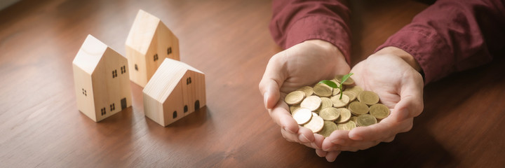 Property investment, Hands holding coins with small house model.