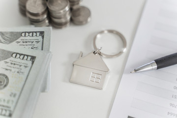 Property investment, small key house with coins and banknote.