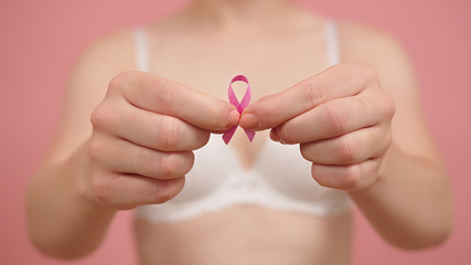 Woman in bra with pink ribbon, breast cancer survivor, pink october, awareness month. High quality photo