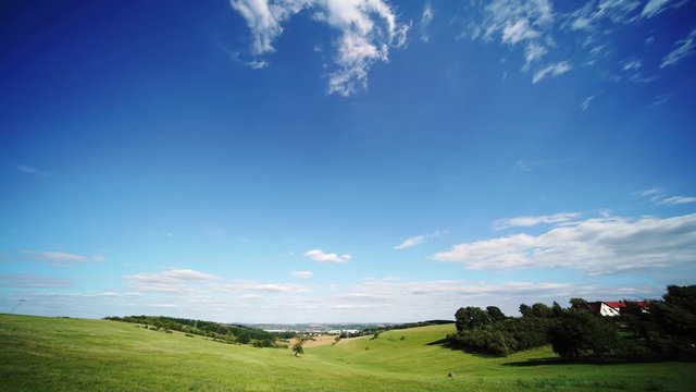 Time lapse of rolling clouds on blue sky over green field background